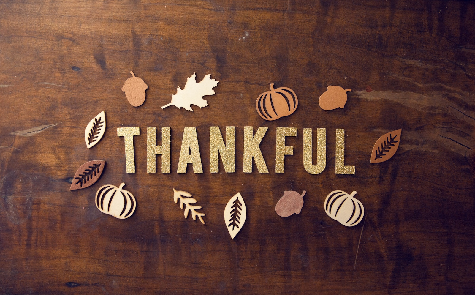 wooden tabletop with thanksgiving decorations and "thankful" written in the center